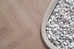 White and grey pebbles arranged in a round container on grey wooden floor