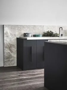 Minimalist residential kitchen featuring a marble backsplash and countertops with dark cabinets.
