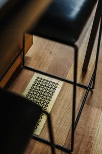 A modern black metal table with a geometric pattern, placed on a wooden floor.