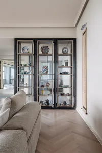 Modern living room with a glass display cabinet showcasing decorative plates and tea sets.
