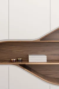 A modern white furniture shelf with wooden components and books.