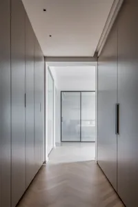 Modern minimalist entryway with polished wooden flooring, white walls, and a glass sliding door.
