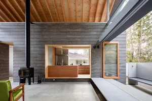 Modern kitchen with concrete and wood materials, featuring an open layout and natural light.