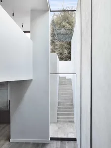 Modern minimalist concrete staircase leading through a white minimalist hallway.