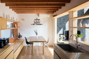 A cozy, modern kitchen dining room featuring rustic wood flooring and furniture, and clean white walls adorned with minimalis