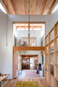 A modern family home featuring wooden interiors and a cozy living room with a couch and a child sitting on it. The home has h