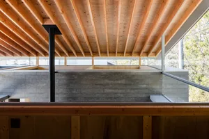 A modern minimalist living space with a wooden ceiling and a concrete interior wall.