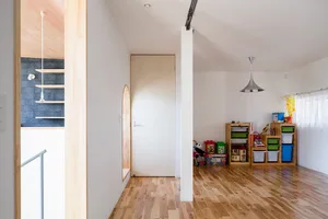 A modern playroom with natural wood flooring and shelves, featuring colorful toys on a wooden floor.