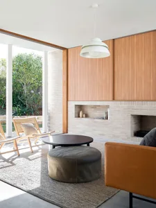 A minimalist living room featuring wooden shelves, a round coffee table, and a leather sofa.