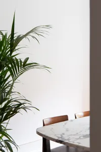 A minimalist dining room featuring a marble table and wooden chairs.