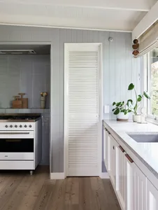 A minimalist kitchen featuring white windows and wooden flooring.