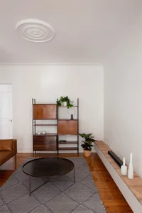 Minimalist living room featuring wooden furniture and metal accents, with a coffee table, vase, and bookcase.