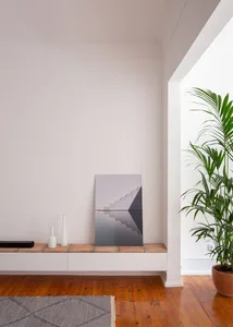 A minimalist living space featuring concrete surfaces, wooden furnishings, and potted green plants.