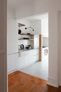 A modern minimalist kitchen with white cabinetry and a concrete floor.