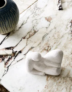 A minimalist interior design showcases a marble terrazzo countertop with a terrazzo figurine and vase.