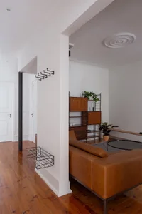 A modern living room featuring a brown leather couch, wooden furniture, and potted plants.