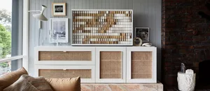 A modern living room featuring a marble coffee table, white cushioned seating, and a detailed white cabinet with rattan accen