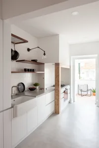 Modern minimalist kitchen with white cabinetry, open shelves, and a sleek countertop.