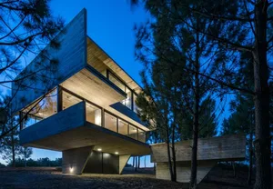 A modern residential building with concrete exterior and large windows at dusk.