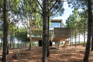 A modern, residential concrete home surrounded by trees and nature.