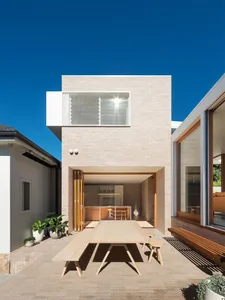 Modern residential exterior with brick façade, large glass windows, and outdoor seating area.