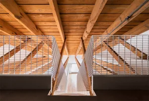 A minimalist staircase featuring wooden beams and metal railings viewed from above.