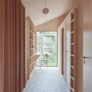 A minimalist interior with wooden shelves, stone walls, and a glass window.