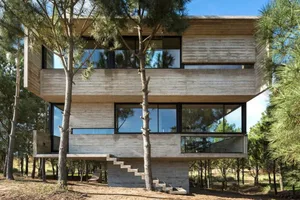 A modern architectural structure made of wood, with large windows and a stepped entryway.