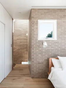 A modern bedroom with brick walls and a wooden floor.