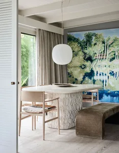 A modern dining room featuring a marble table with wood chairs and a large, colorful mural in the background.