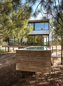 Modern house exterior featuring a concrete structure surrounded by trees.