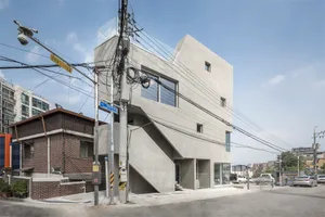 A modern residential building with a concrete exterior and glass windows.