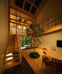 A photograph of a wooden interior space with a tree and dining table.