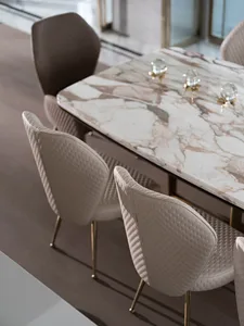 Modern dining room with white and brown marble table and leather upholstered chairs with brass legs.