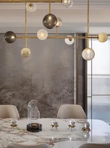 Modern dining room featuring marble table, glass light fixtures, and brass accents.