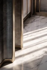A modern interior design featuring a marble floor with sleek, metallic accents and natural light streaming through large wind