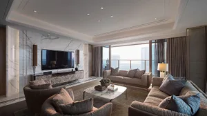 A modern living room featuring marble walls and furniture, with large windows overlooking a cityscape.