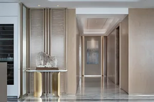 A modern entrance hall with marble flooring and walls, featuring a contemporary sculpture.