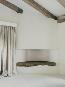 A minimalist interior featuring a corner stone fireplace with a concrete finish.