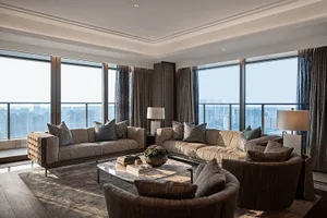 A contemporary living room with glass walls, modern furniture, and a large window overlooking the city.