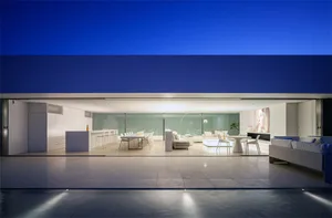 Modern living room with white furniture, floor-to-ceiling windows, and minimalistic design.