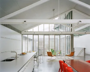 Modern minimalist kitchen with metal cabinets, glass walls, and red wooden tables