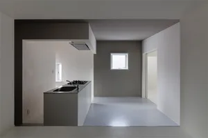 Modern minimalist kitchen with concrete island and floor, white walls, and gray accents.