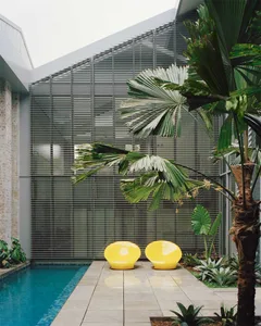 A modern outdoor space featuring glass bricks, a swimming pool, and palm trees. The deck is designed with a minimalist aesthe