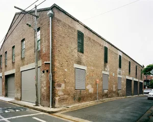 A street view of a brick building with roller shutters and a street light.