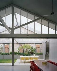 A minimalist living space with concrete walls, floor-to-ceiling windows, and indoor plants.
