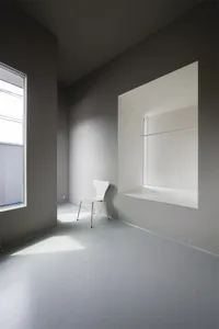 A minimalist white interior space with layered lighting and grey walls.