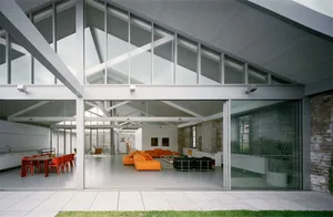 A modern living room featuring glass walls, brick walls, and concrete flooring and ceiling.