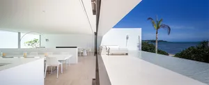 Modern living room interior with white marble floor and walls, featuring contemporary furniture and large windows overlooking