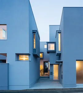 Modern residential building with concrete exterior and illuminated windows at dusk.